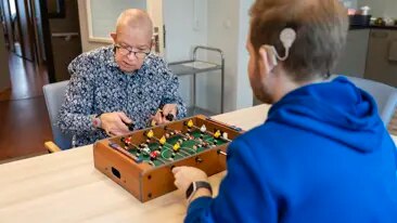 Wonen bij Kentalis: een plek waar je jezelf kunt zijn Medewerker en bewoner doen een spelletje