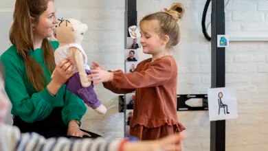 Leren met handpop Jules bij de vroegbehandeling Medewerker geeft handpop Jules aan een kind